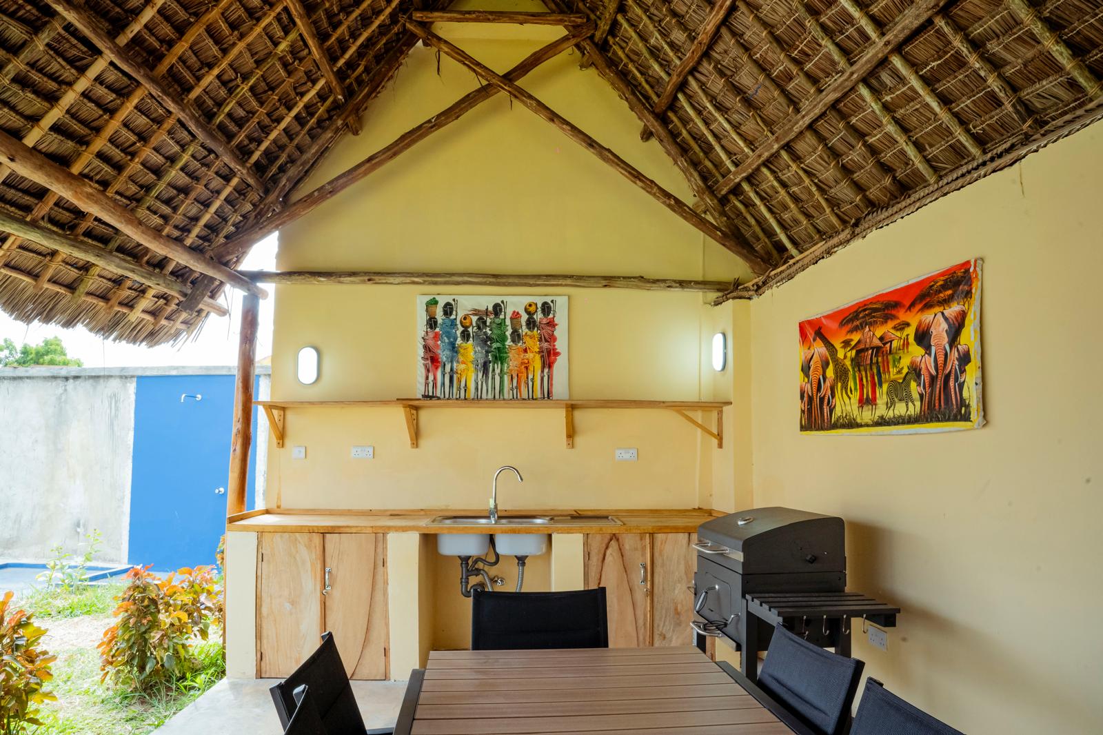 Cuisine d'été et espace repas sous la grande paillote au toit de chaume à Zanzibar