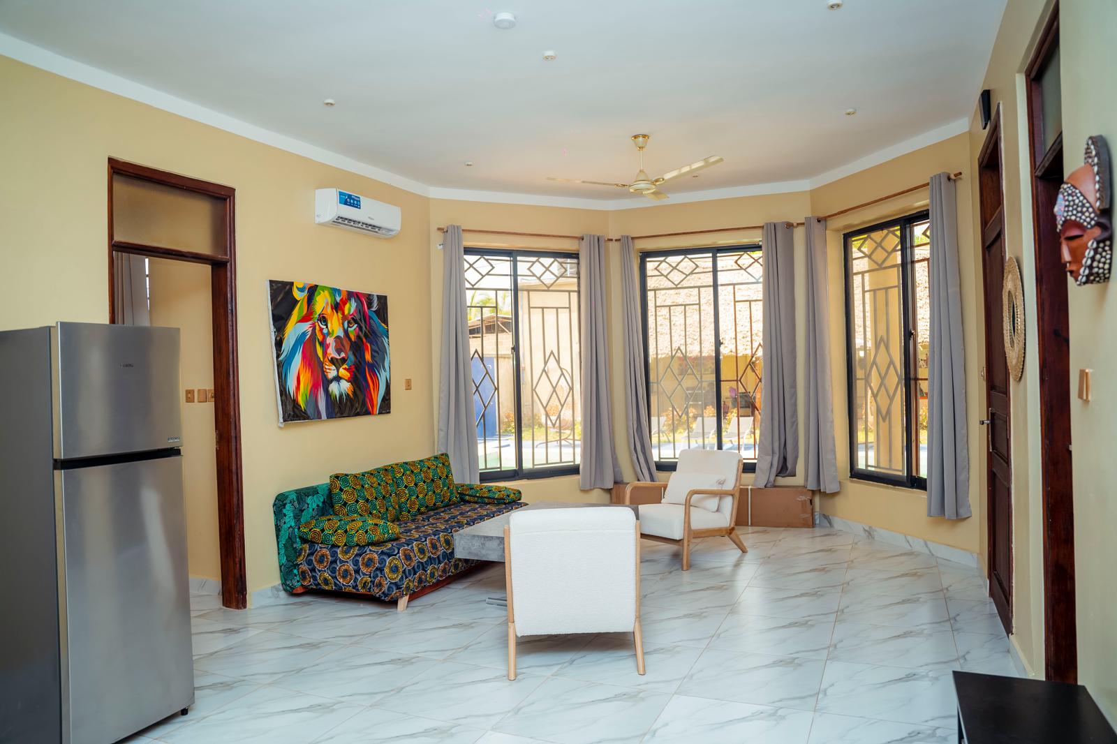 Salon intérieur lumineux de la villa avec grandes baies vitrées et sol en marbre à Kiwengwa